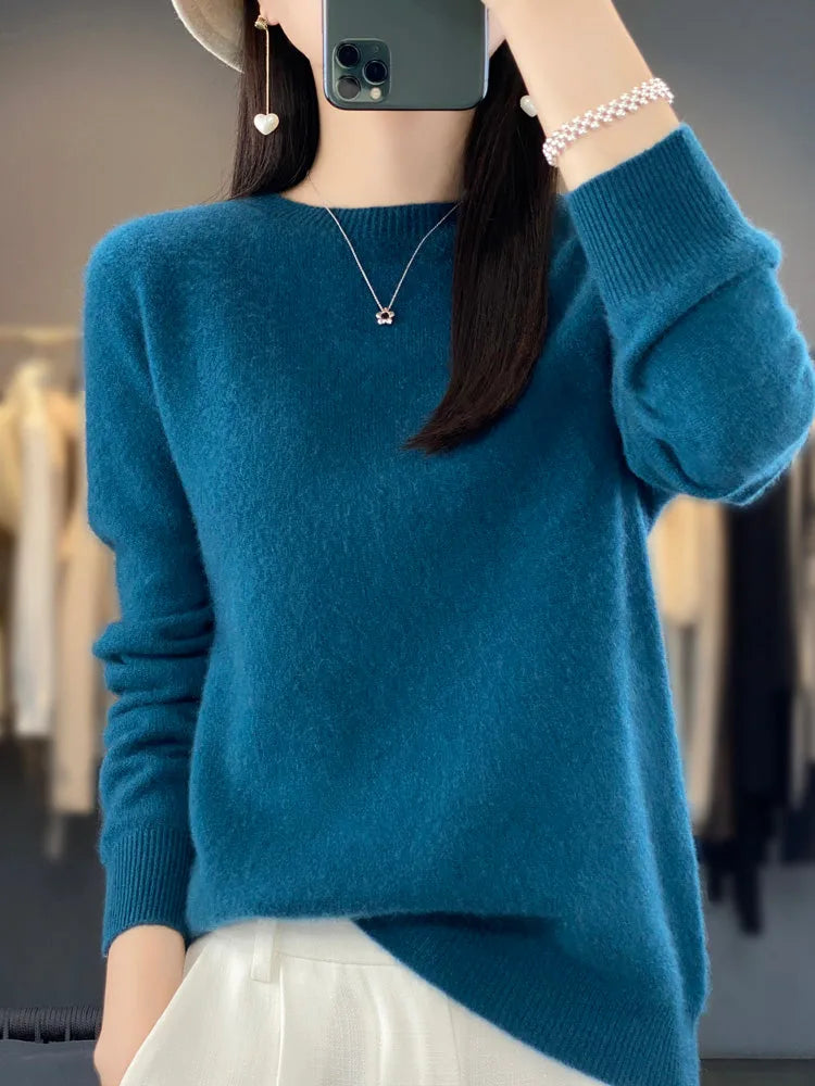Teal blue knit jumper worn with ribbed cuffs and a subtle side hem slit over white trousers