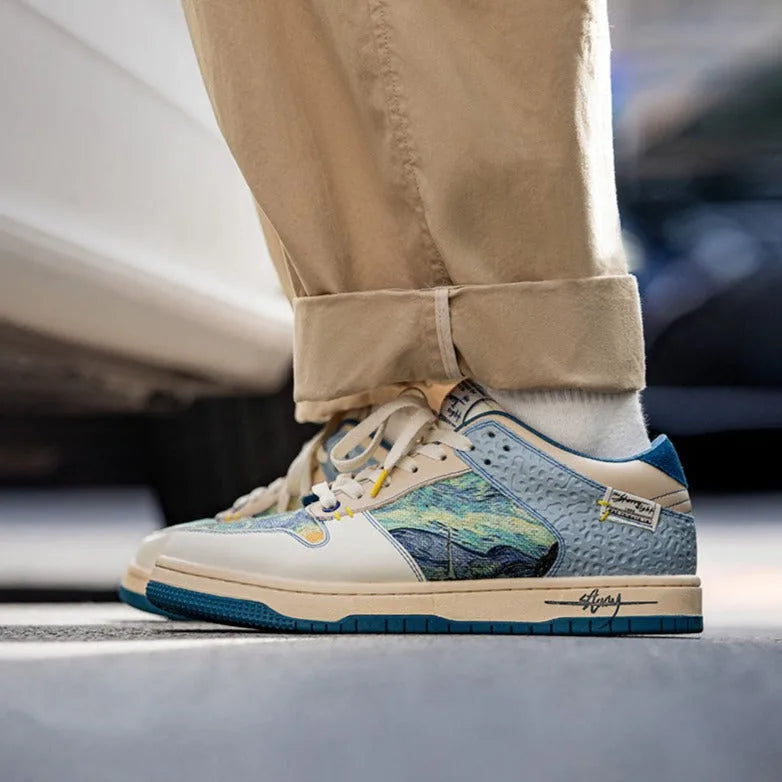 Man wearing cream and blue Starry Night print trainers with rolled beige trousers on a city pavement