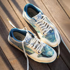 Top down view of a matching pair of art print trainers with cream laces on a wooden deck