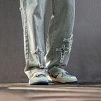 Close-up of ripped light denim jeans worn with the blue and cream Starry Night trainers