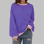 Front view showing relaxed oversized fit of striped sweatshirt paired with ripped denim jeans