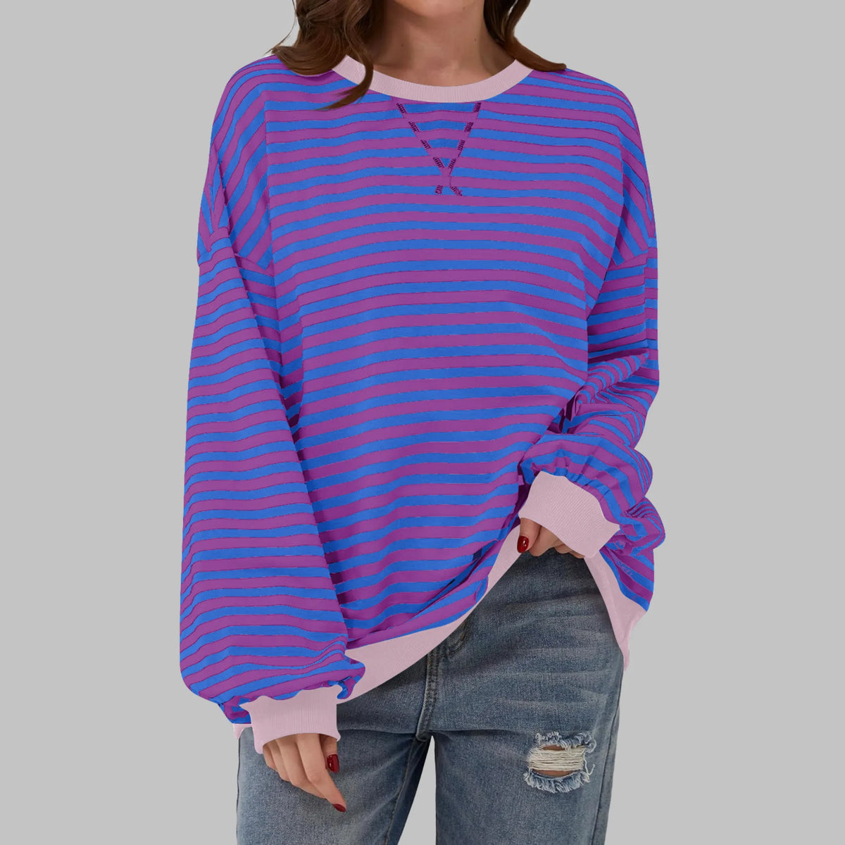 Front view showing relaxed oversized fit of striped sweatshirt paired with ripped denim jeans