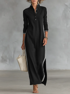 Front view of a woman in a black long-sleeve maxi shirt dress with white striped trim and a button-down collar