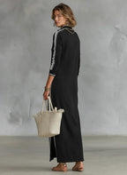Back view of the black maxi dress showing the stand collar, raglan sleeves and side split at the hem