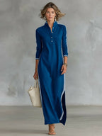 Woman modelling a royal blue long-sleeve maxi dress with white side stripes and buttoned collar detail