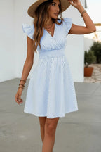 Close-up side view of the striped dress paired with a straw hat, showing the smocked waist detail outdoors.