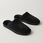 Side view of black suede slipper with tan collar, fur lining and brown sole