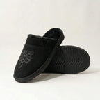 Three-quarter view of black suede slipper with tan cuff and embroidered toe stitching