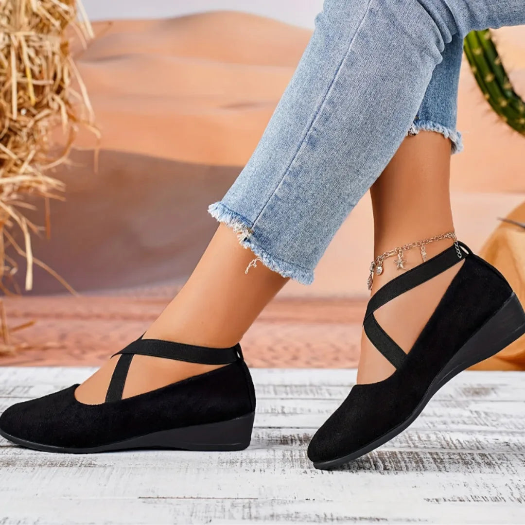 Woman stepping forward in black crisscross-strap ballet flats paired with cropped jeans, desert backdrop