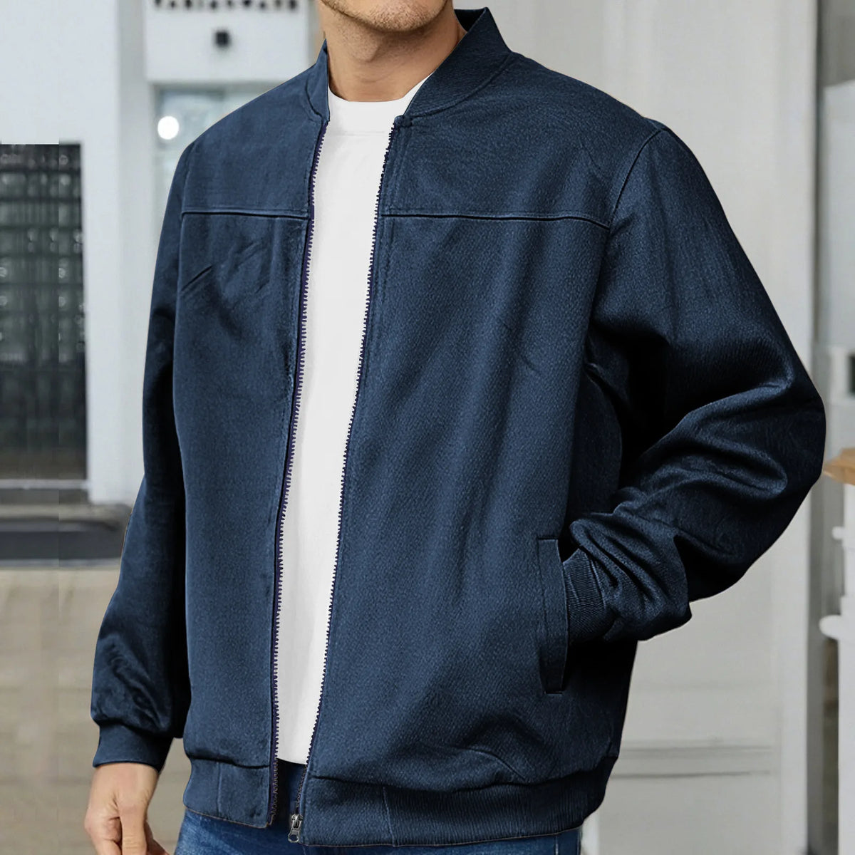 Close-up of a navy bomber jacket worn open over a white t-shirt, highlighting the smooth texture and zip detail