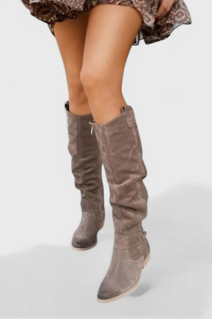 Grey suede knee-high boots with tie detail at the top edge and pointed toe, worn with a patterned skirt