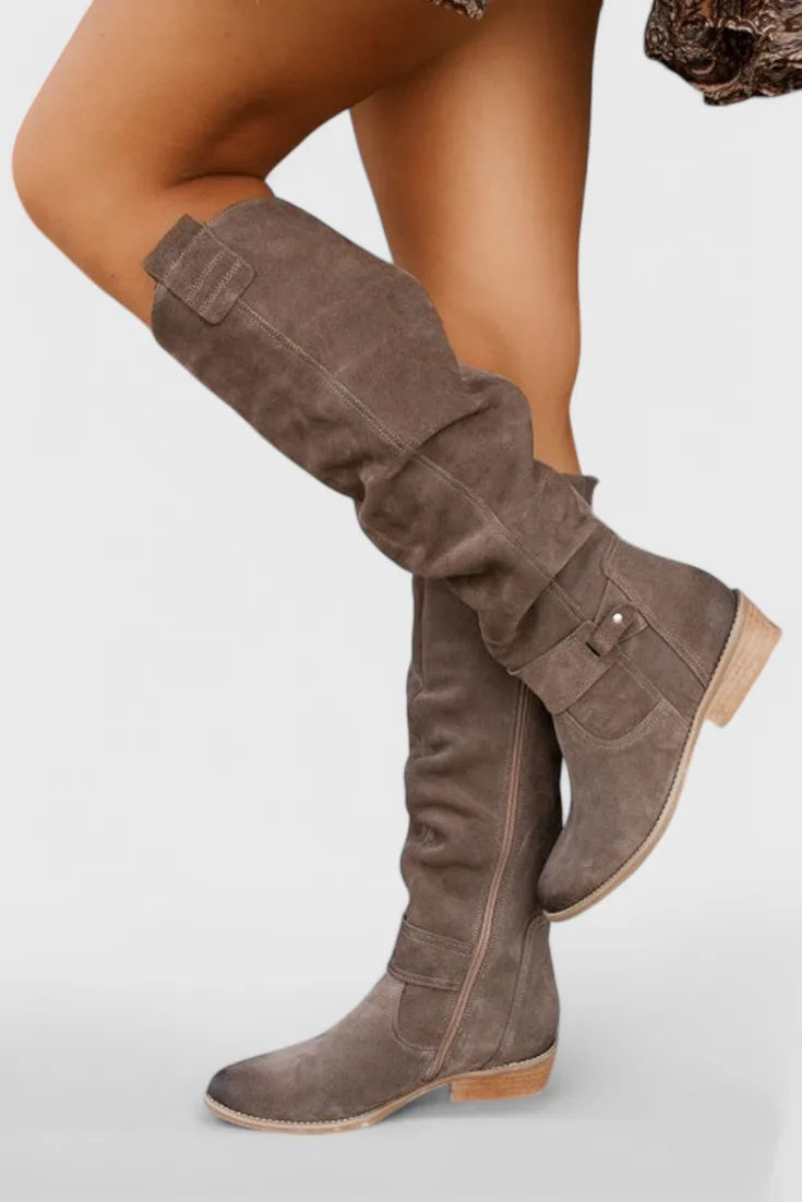 Grey suede knee-high boot side profile highlighting slouchy shaft and buckle detail near the ankle