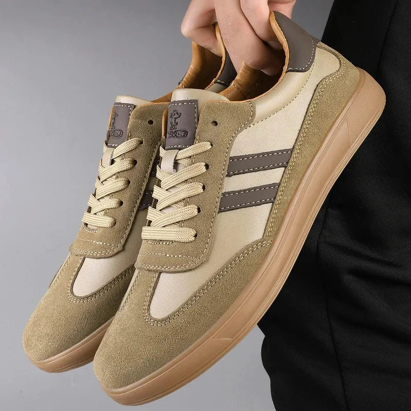 Khaki suede and leather panel trainer held by hand, showing gum sole and tan tongue lining detail
