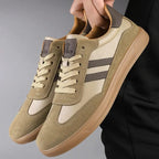 Khaki suede and leather panel trainer held by hand, showing gum sole and tan tongue lining detail