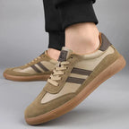 Close-up side angle of khaki suede trainer on foot with dark stripe detailing and cotton laces