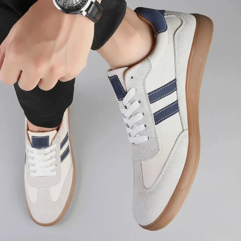 Close-up of off-white trainer worn on foot alongside matching pair, navy stripe and lace detail visible