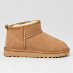 Side view of a tan suede mini ankle boot with plush cream faux-fur lining and ribbed grip sole