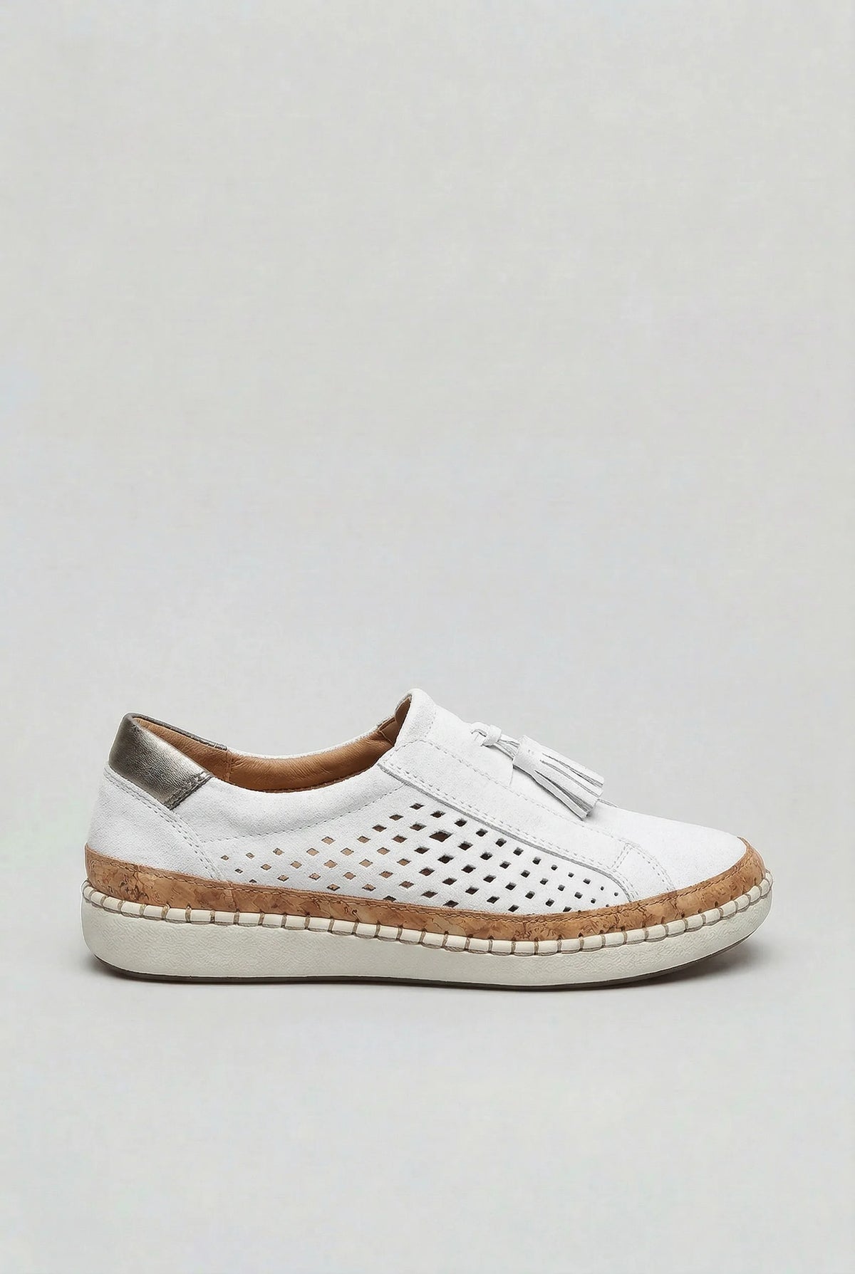 Side view of a white suede slip-on trainer with perforated cut-out design, tassel trim and cork platform sole