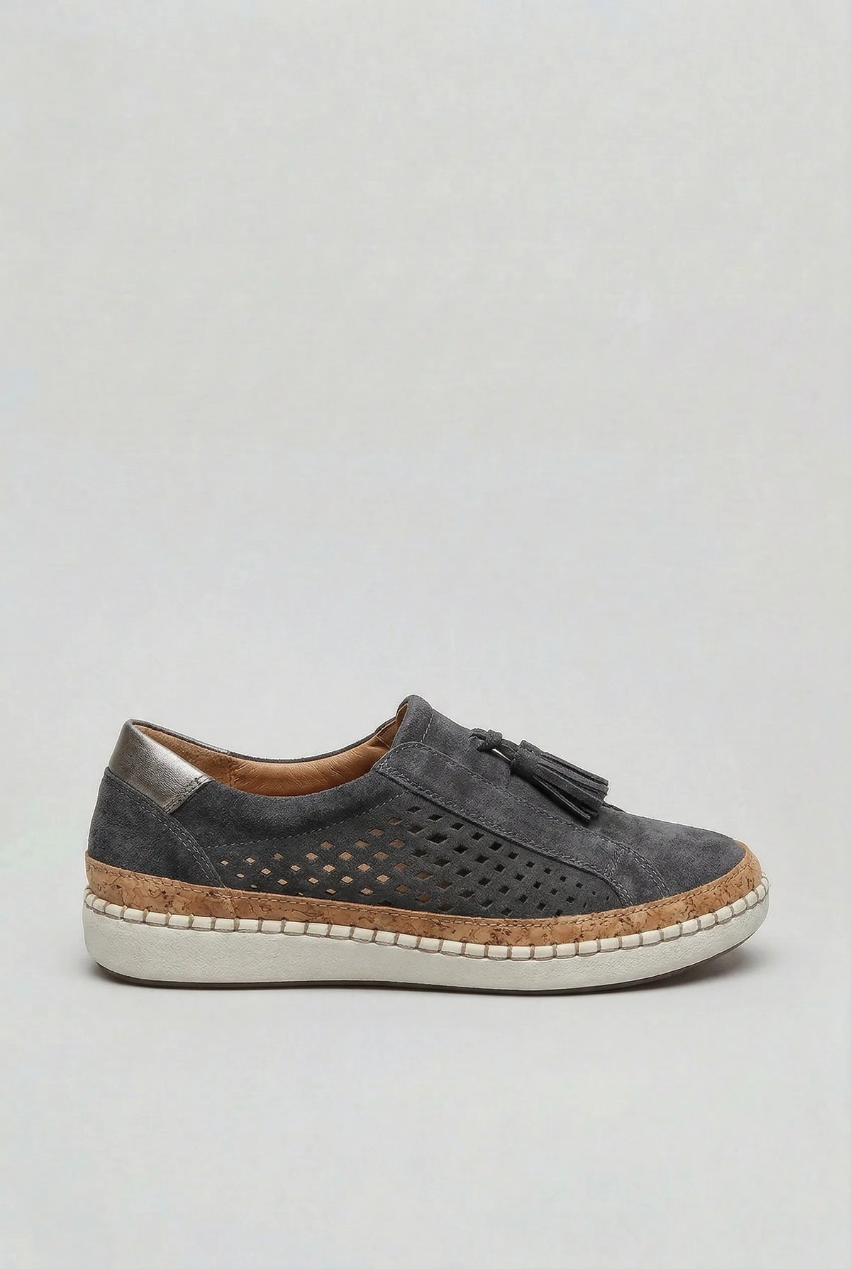 Full side profile of a slip-on trainer highlighting the metallic heel tab, suede tassel and cork-wrapped platform