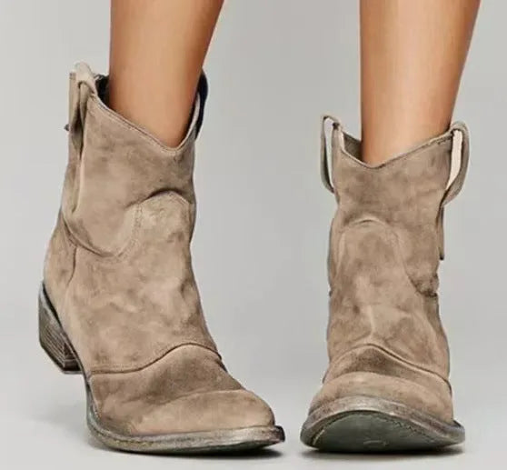 Front view of taupe suede ankle boots with side pull tabs and stacked block heel, worn on bare legs