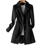 Black tailored trench coat on hanger with notched collar and button-front fastening, shown open over a white top