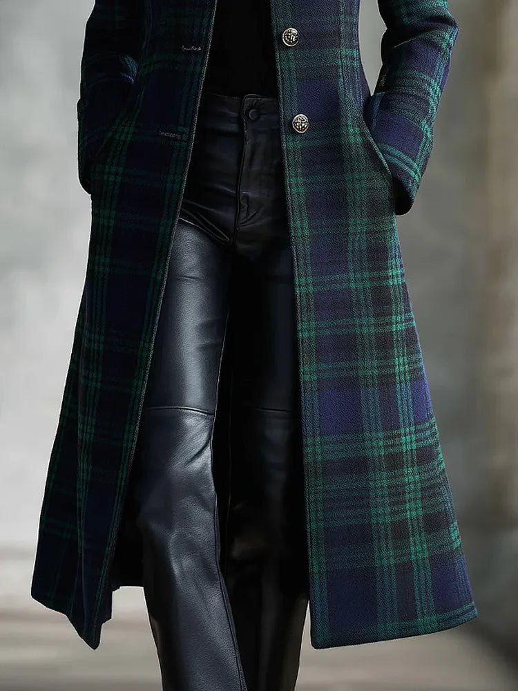 Side view of the long checked coat showing the flowing midi length and welt pocket detail over leather trousers