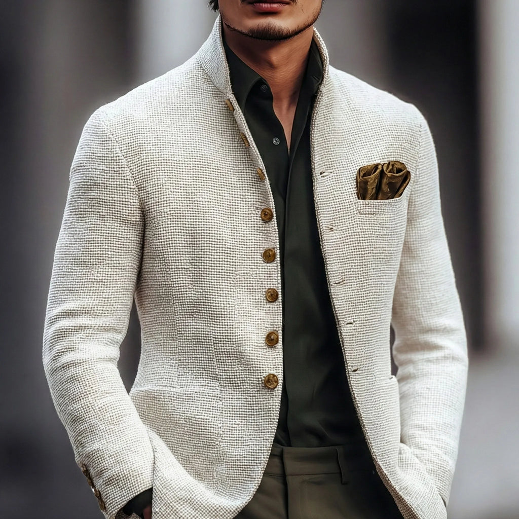 Man wearing a textured white stand-collar jacket over an olive shirt, styled with a bronze pocket square, front view