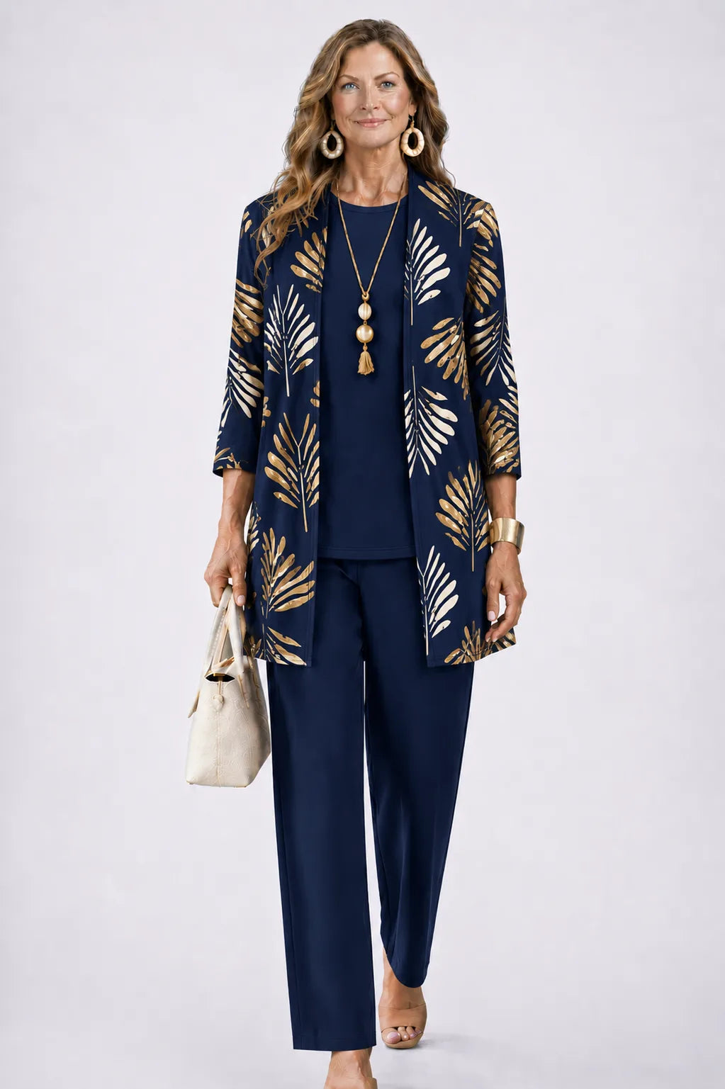 Woman wearing a navy longline cardigan with gold leaf print, over a navy top and matching navy trousers