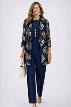 Woman wearing a navy longline cardigan with gold leaf print, over a navy top and matching navy trousers