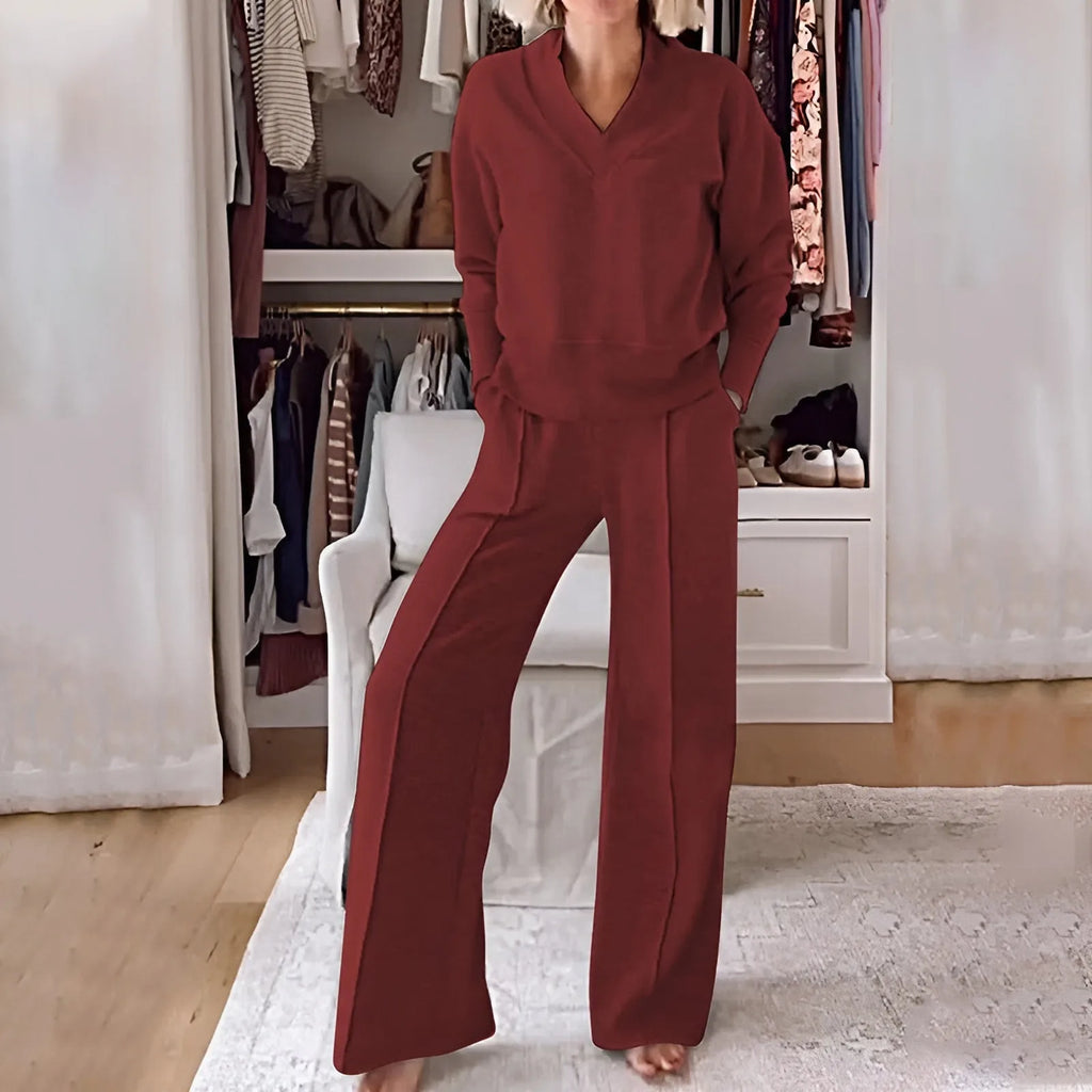 Front view of the rust red V-neck jumper paired with matching wide-leg trousers in a dressing room setting