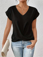 Woman modelling a black V-neck top with cap sleeves and a soft twist-front hem over blue jeans