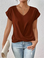 Rust brown V-neck top with cap sleeves and draped twist-front styling, worn with ripped denim jeans