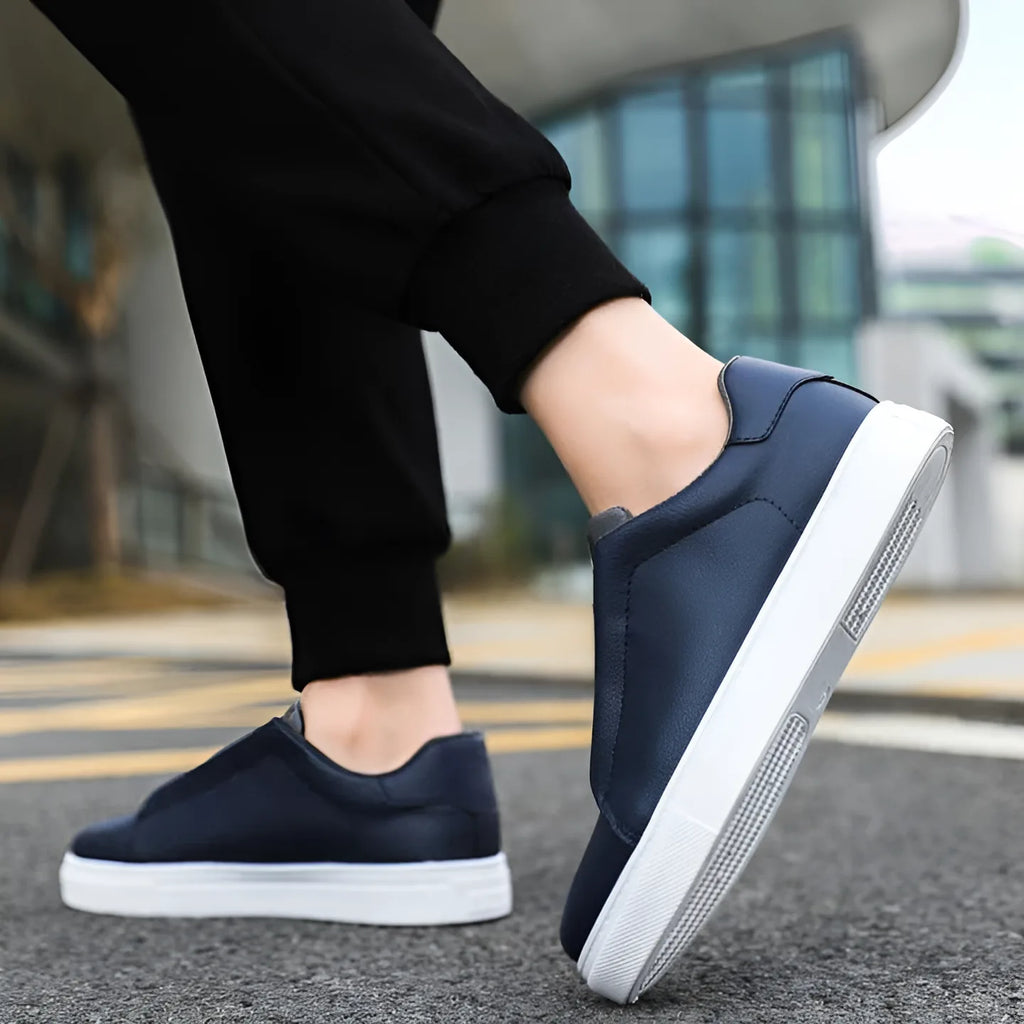Close-up of foot stepping into a navy blue slip-on style trainer with grey elastic panel