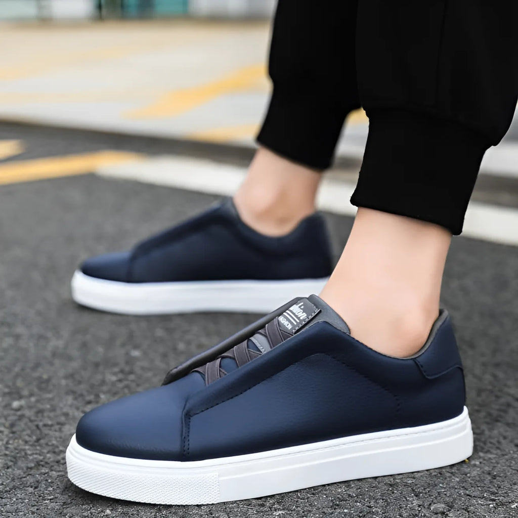 Side view of two navy blue leather trainers worn while walking on pavement