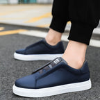 Side view of two navy blue leather trainers worn while walking on pavement