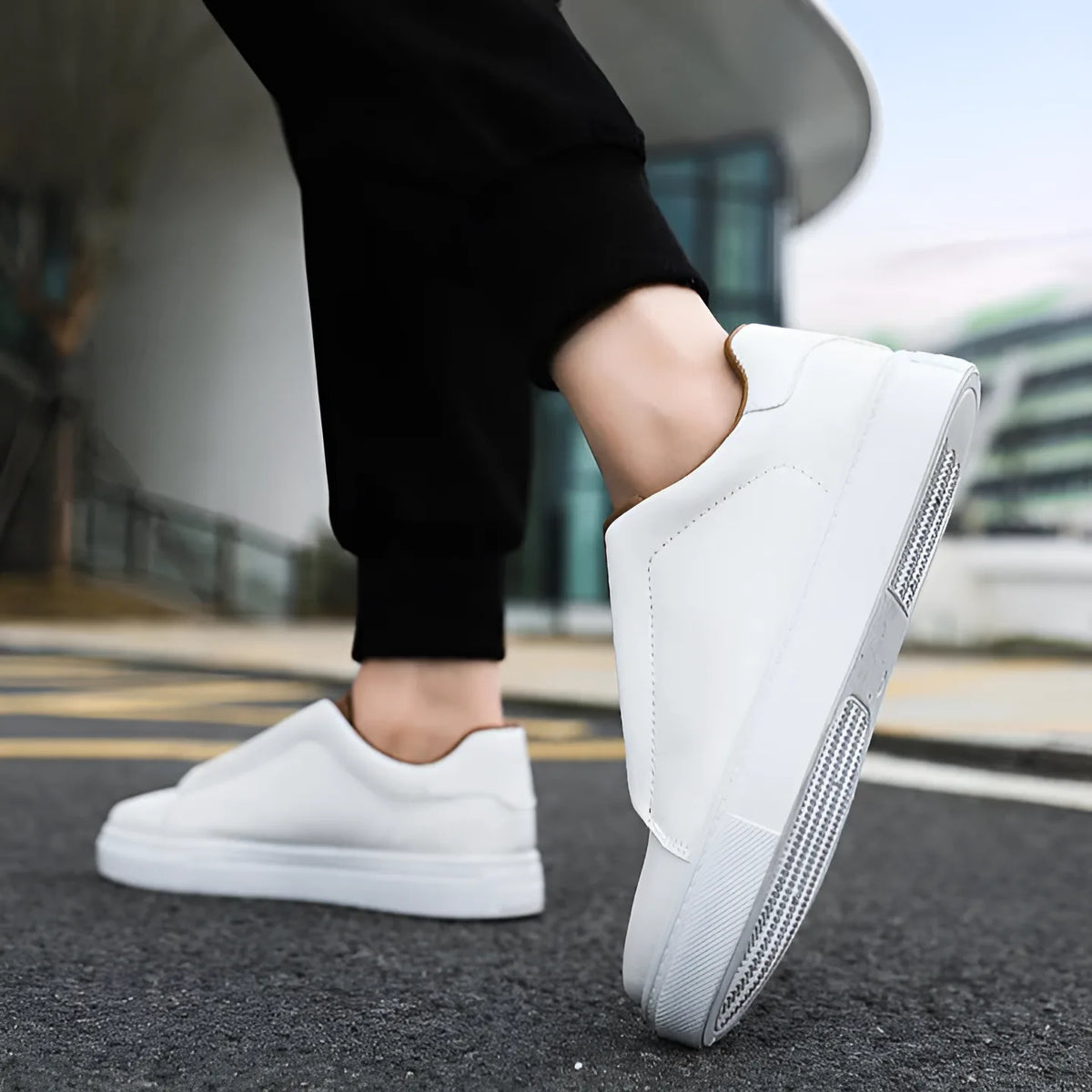 Close-up of white trainer mid-step showing thick white ridged outsole and tan ankle trim