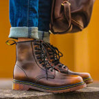 Man wearing ember brown leather lace-up boots with rolled denim jeans, close-up on the ankle and laces