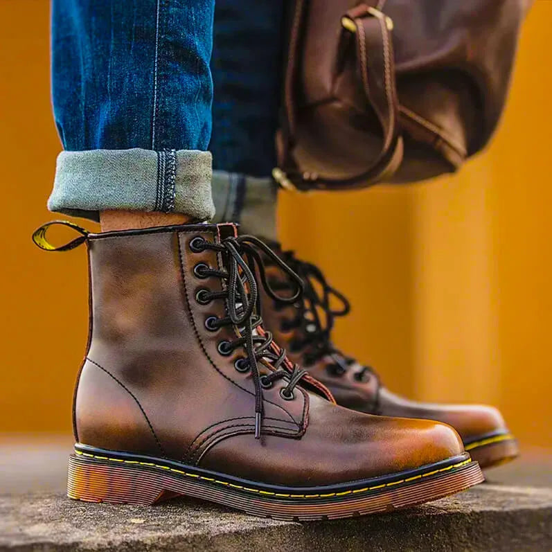 Man wearing ember brown leather lace-up boots with rolled denim jeans, close-up on the ankle and laces