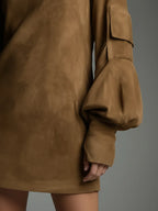 Detail shot of the cargo-style pocket on the balloon sleeve cuff and the hip pocket of the tan suede dress