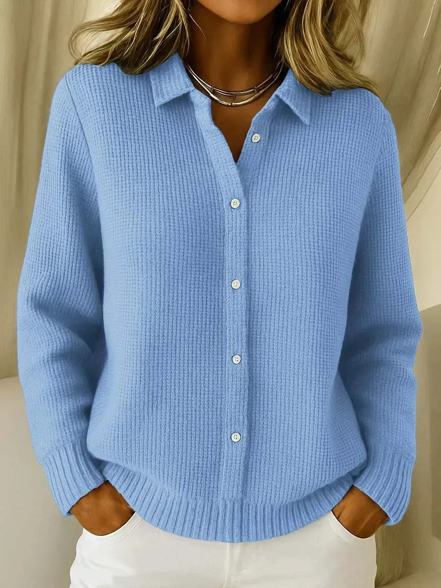 Close-up front view of a light blue waffle-knit cardigan with collared button-front and long sleeves, worn over white trousers.