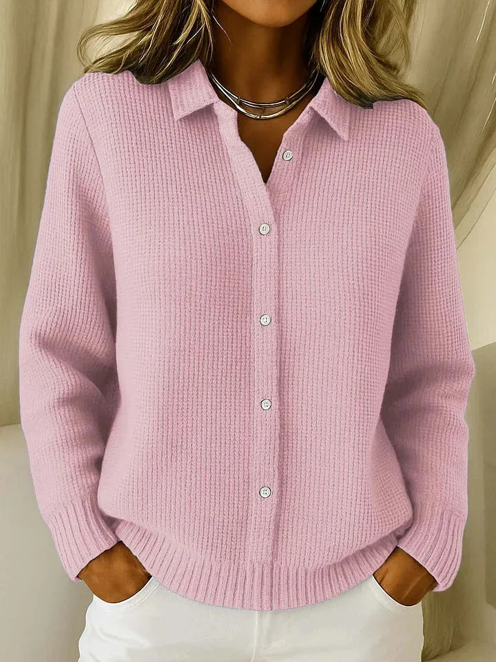 Pink waffle-knit collared cardigan shown open-necked with white buttons, styled with a layered chain necklace.