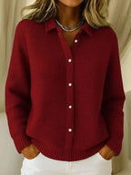 Dark red waffle-knit cardigan with pointed collar and button placket, paired with white trousers for a casual look.