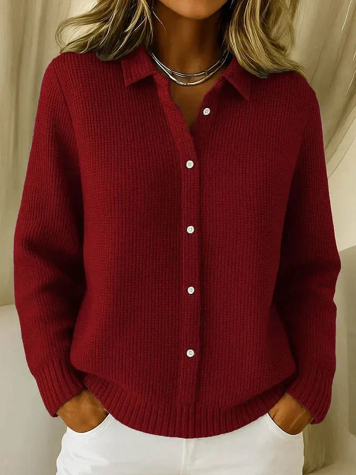 Dark red waffle-knit cardigan with pointed collar and button placket, paired with white trousers for a casual look.