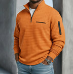 Close-up front view of an orange quilted waffle-texture quarter-zip jumper with a zip chest pocket and sleeve pocket