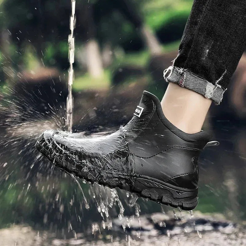 Close-up of water splashing off a black waterproof chelsea boot worn with rolled jeans