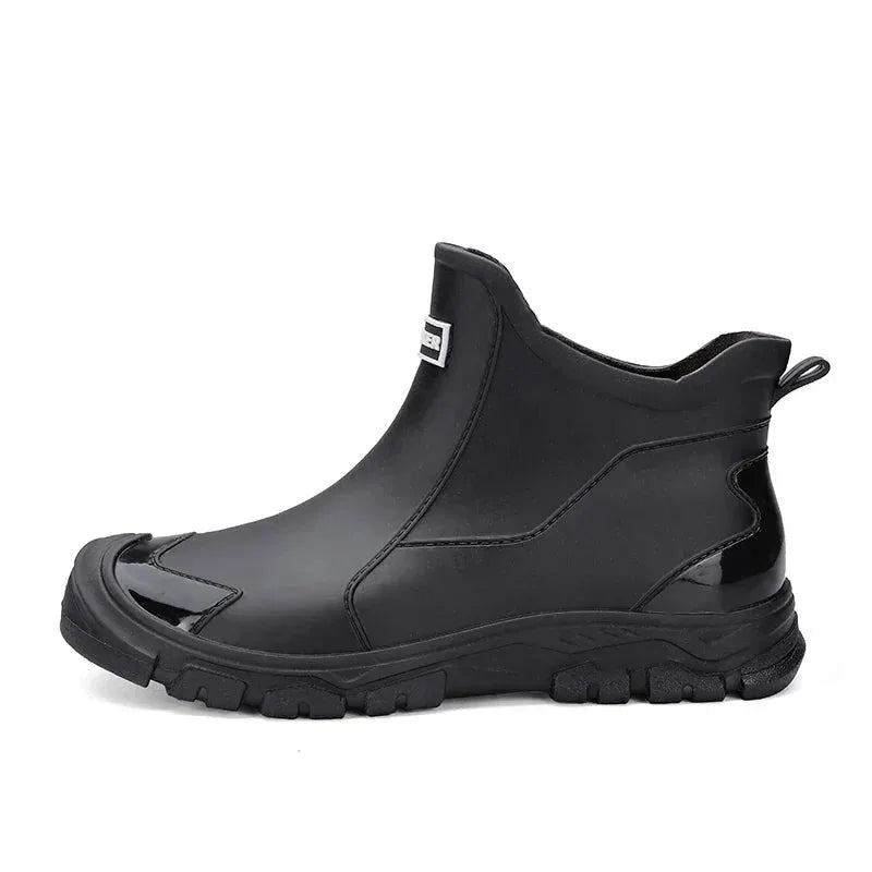 Side profile of a black rubber chelsea boot on a plain white background