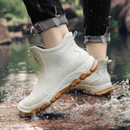Rear view of beige chelsea boot with tan sole worn while stepping through a puddle