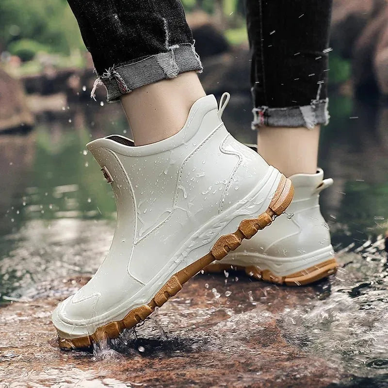 Rear view of beige chelsea boot with tan sole worn while stepping through a puddle