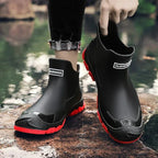 Black and red chelsea boots being lifted by hand, showing textured toe cap and red sole
