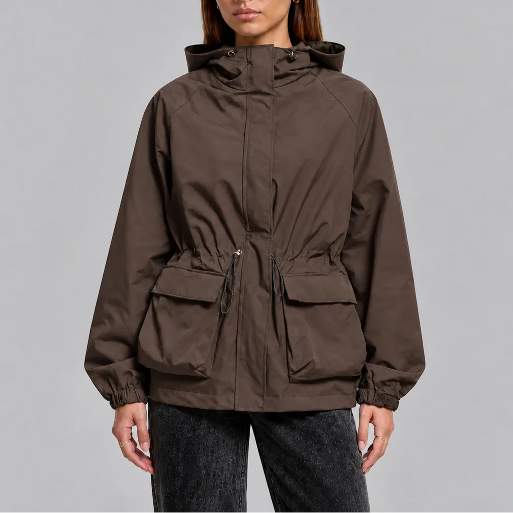 Front view of a woman wearing a brown hooded waterproof jacket with drawstring waist and front flap pockets